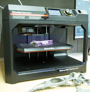 A section, or slice, of a 3 D skull can be seen in the center of the Makerbot Replicator.