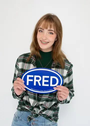 Fredonia student Caitlyn Hampe smiling and holding a FRED sign